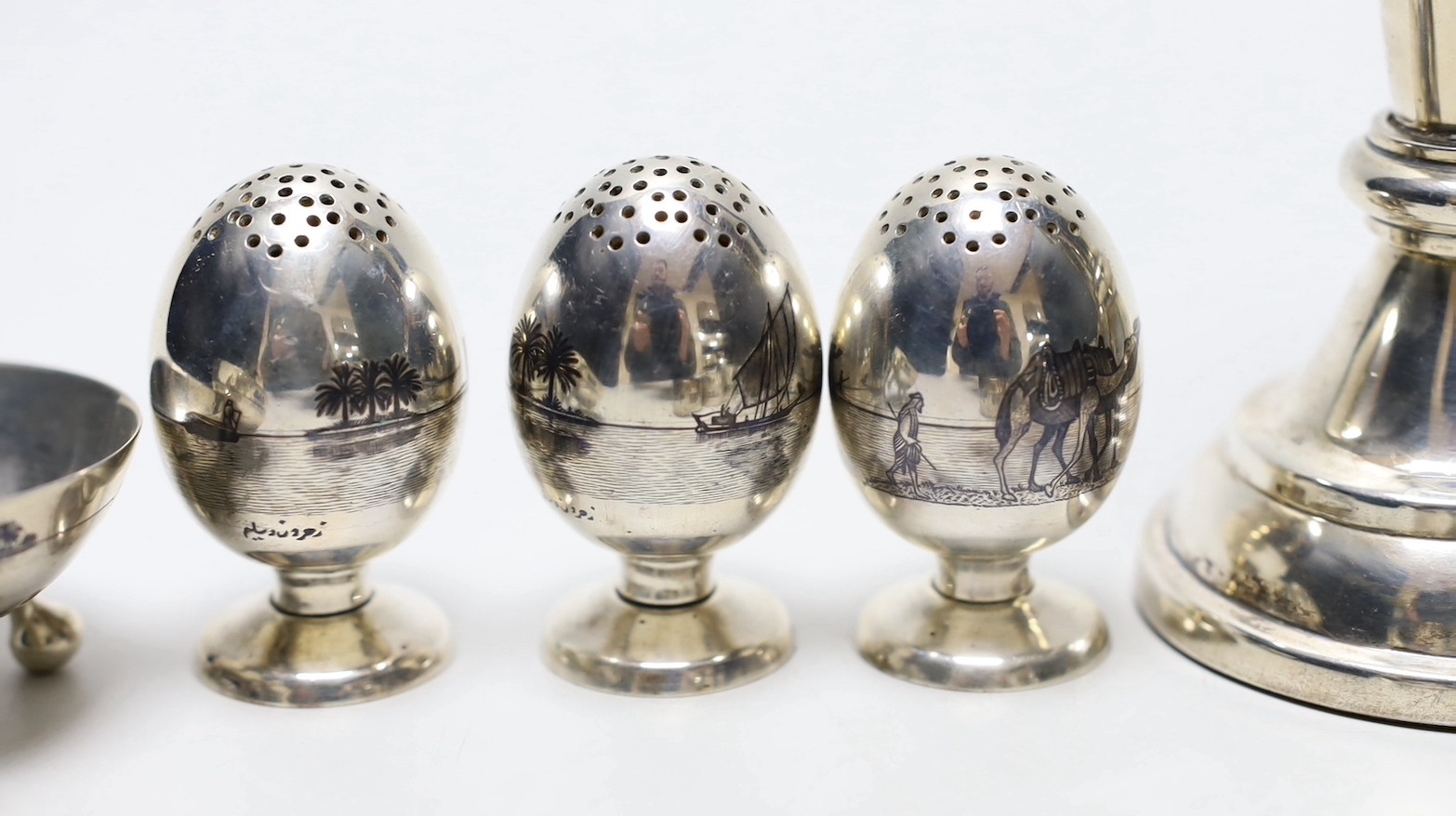 Thirteen assorted Iraq white metal and niello condiments, circular box, five similar napkin rings, a brooch and a pair of similar (damaged) candlesticks.